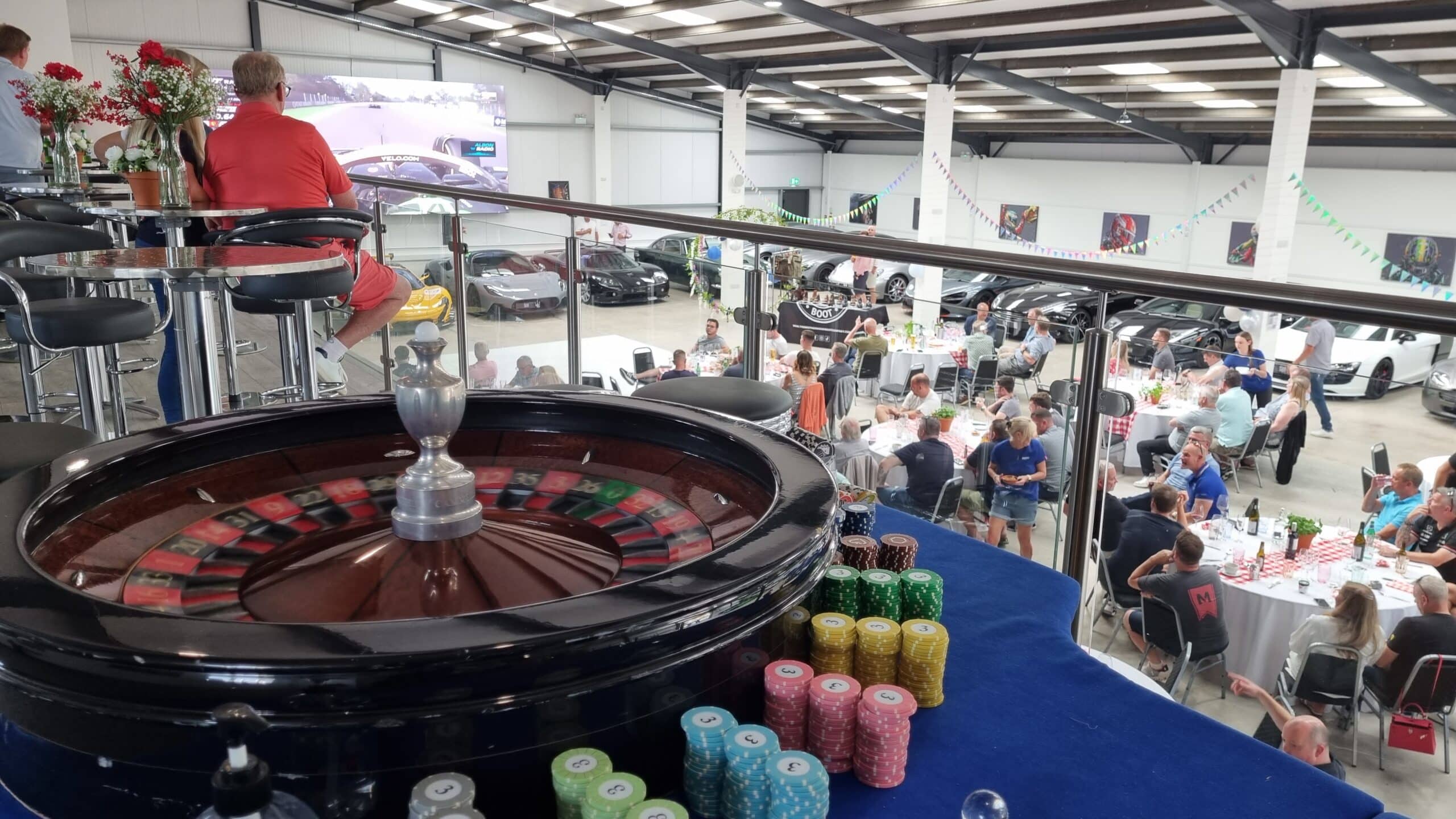 Roulette wheel and chip stacks overlooking a corporate event in a supercar showroom