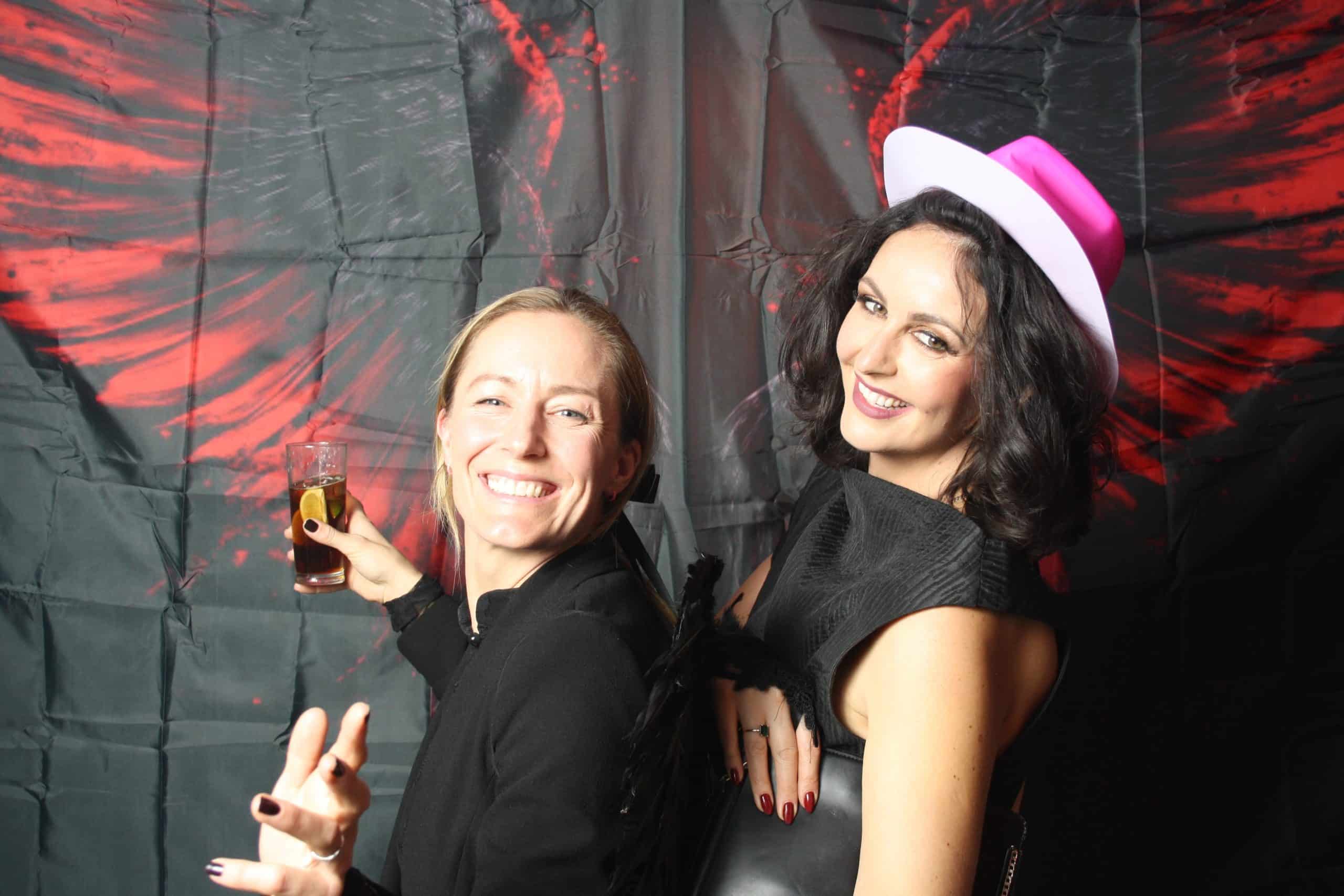 Photobooth 15 Two women pose playfully, smiling with drinks.