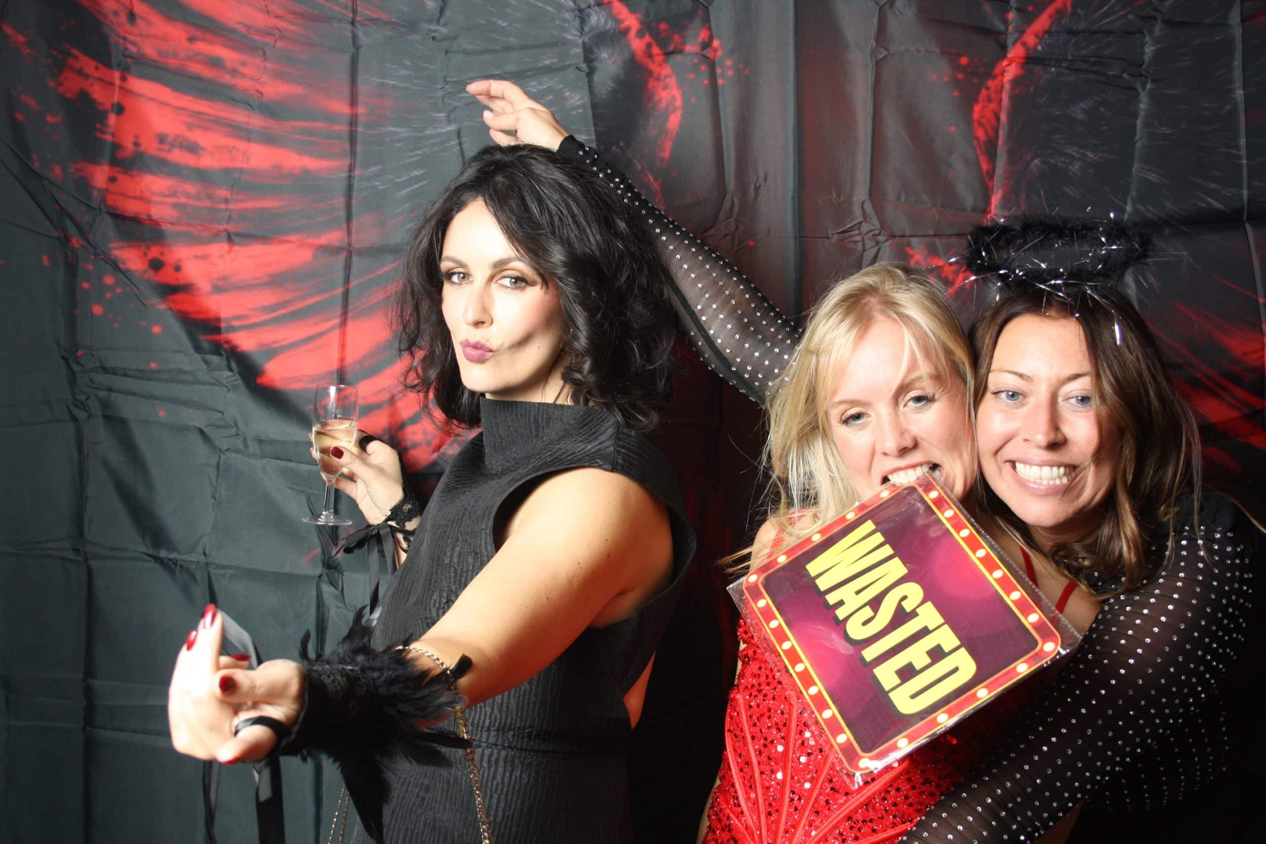 Photobooth 17 Three women posing playfully with drinks and props.