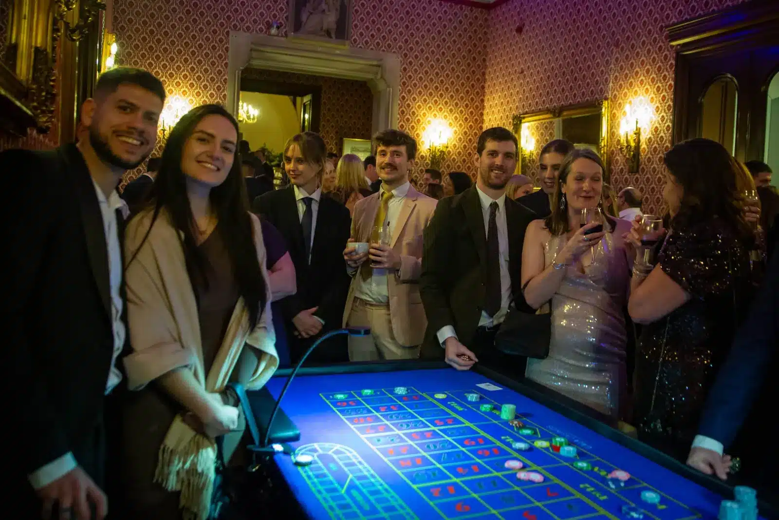 Guests smiling around a roulette table in a grand venue